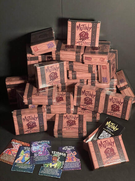 Irregular stack of Mutiny boxes, and a few cards laid up-front next to an open box.